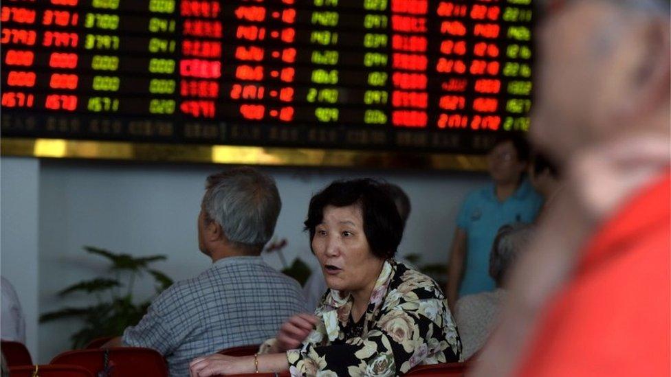 Investors monitor screens showing stock market movements at a brokerage house in Shanghai on August 13, 2015.