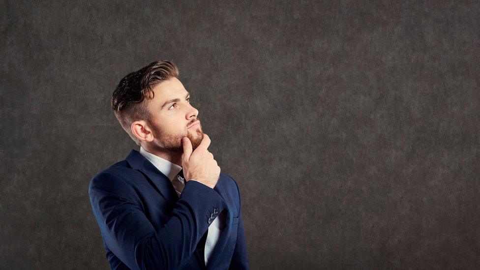 A young businessman in a suit, thinking