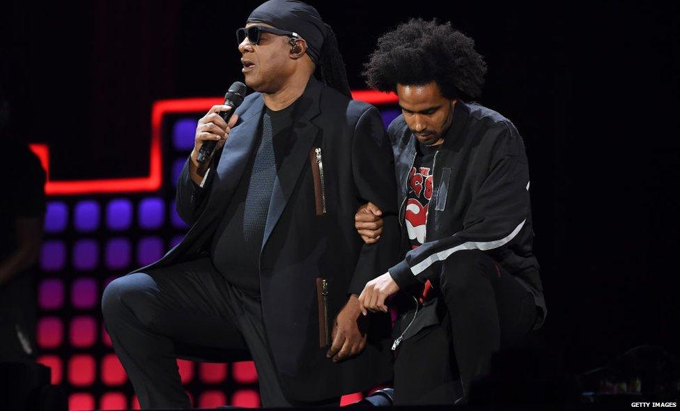 Stevie Wonder and his son kneeling