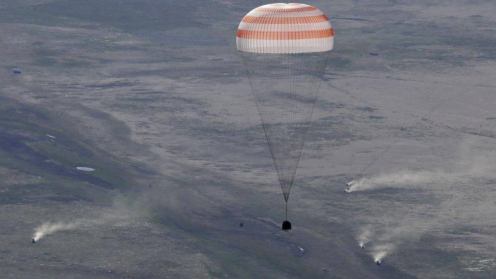 The Soyuz capsule descends by parachute