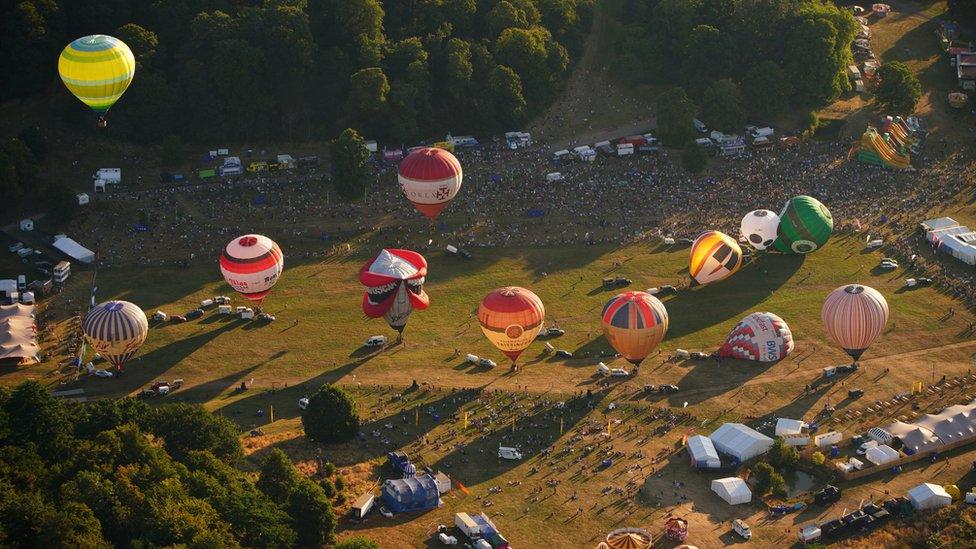 Looking down from a hot air balloon onto the site at Ashton Court with balloons below