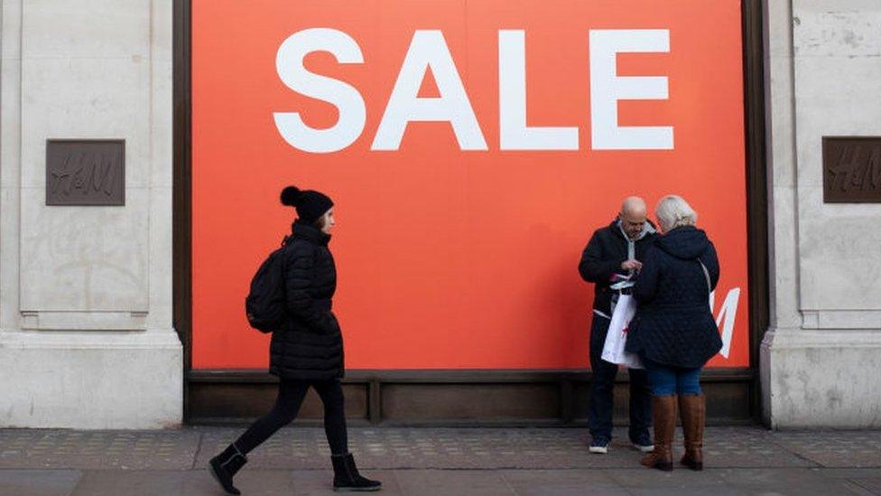 Shoppers walking past sale sign