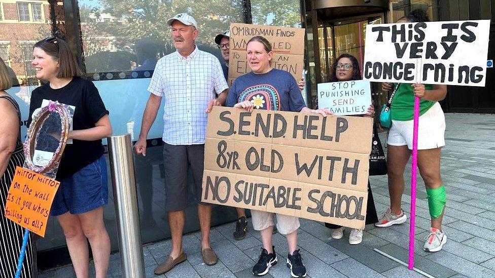 Parents with placards standing outside office building