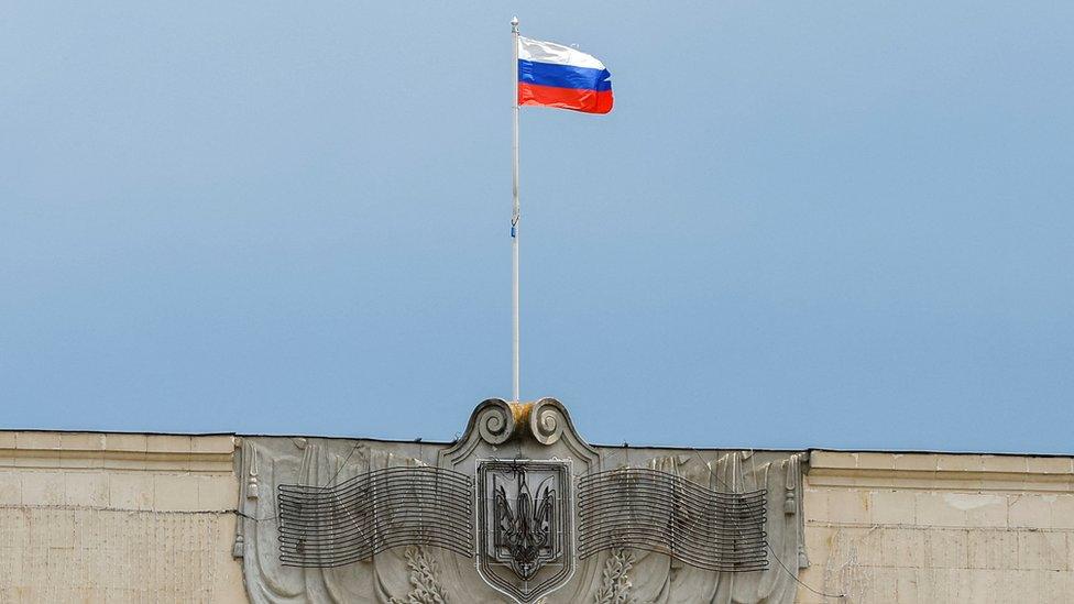 A Russian flag flies above the Ukrainian coat of arms in a former regional council's building in Kherson