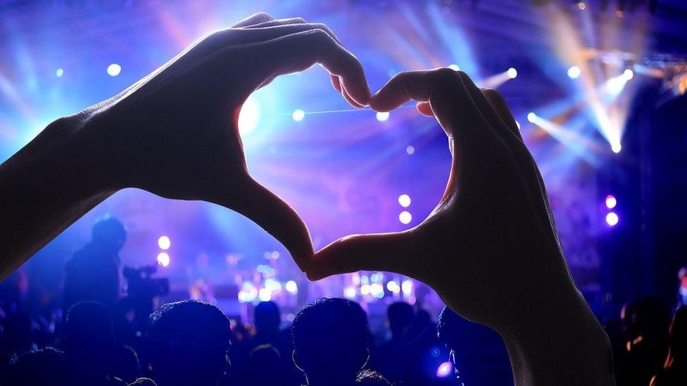 person-with-love-heart-hands-at-concert.