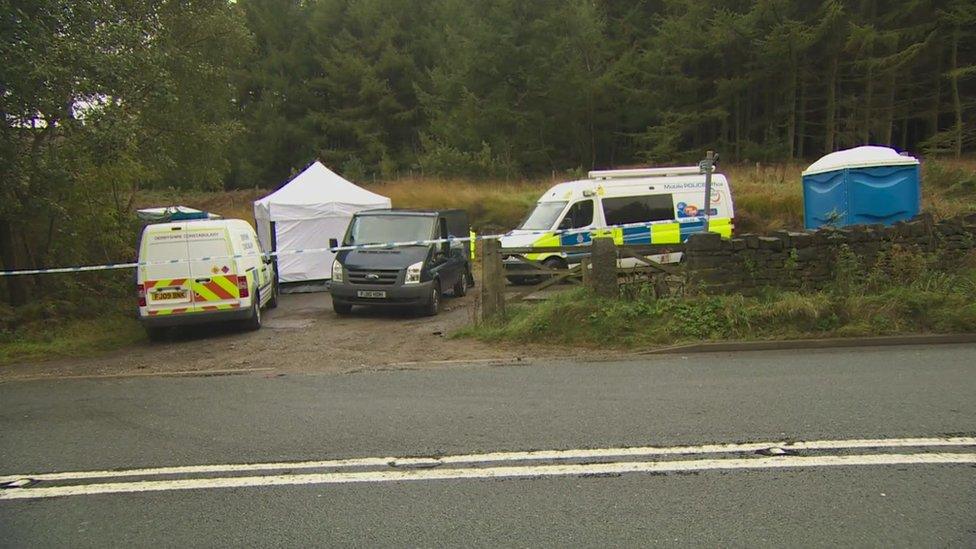 Police vehicles and forensic tents in the lay-by where the body was found