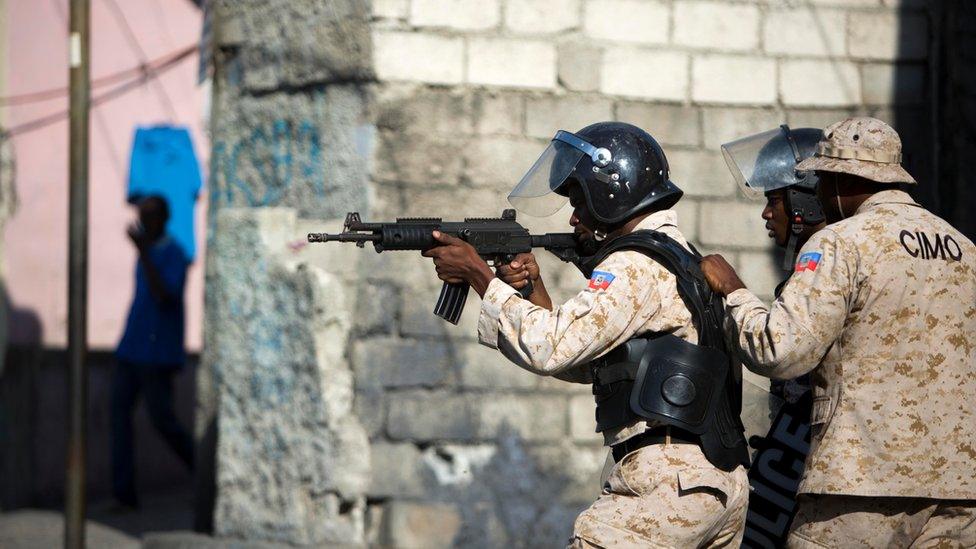 A national police officer points his gun at supporters of presidential candidate Maryse Narcisse protesting final election results in Port-au-Prince, Haiti