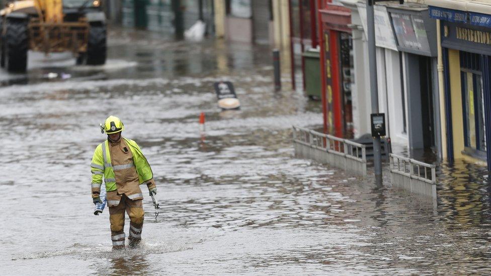 A fire officer wades through flood water in Newton Stewart, Scotland,