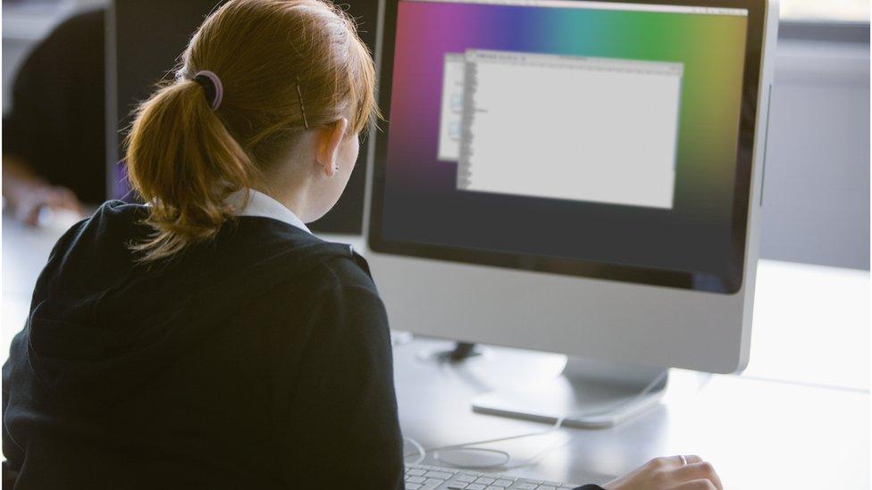 Girl sitting at a computer screen in a classroom