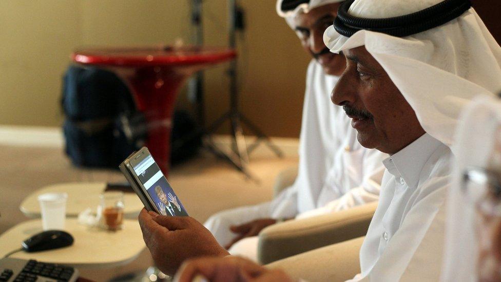 File photo showing a trader using his phone to follow news of the US presidential election result in Doha, Qatar (9 November 2016)