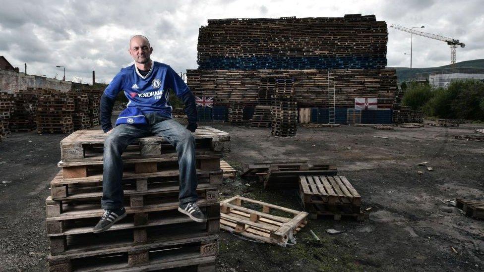 Davy McGrotty watches over the unfinished bonfire in an area known as The Village, in South Belfast.