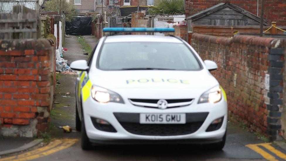 Police car and black tarpaulin in alleyway