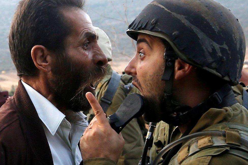 A Palestinian man and an Israeli soldier argue