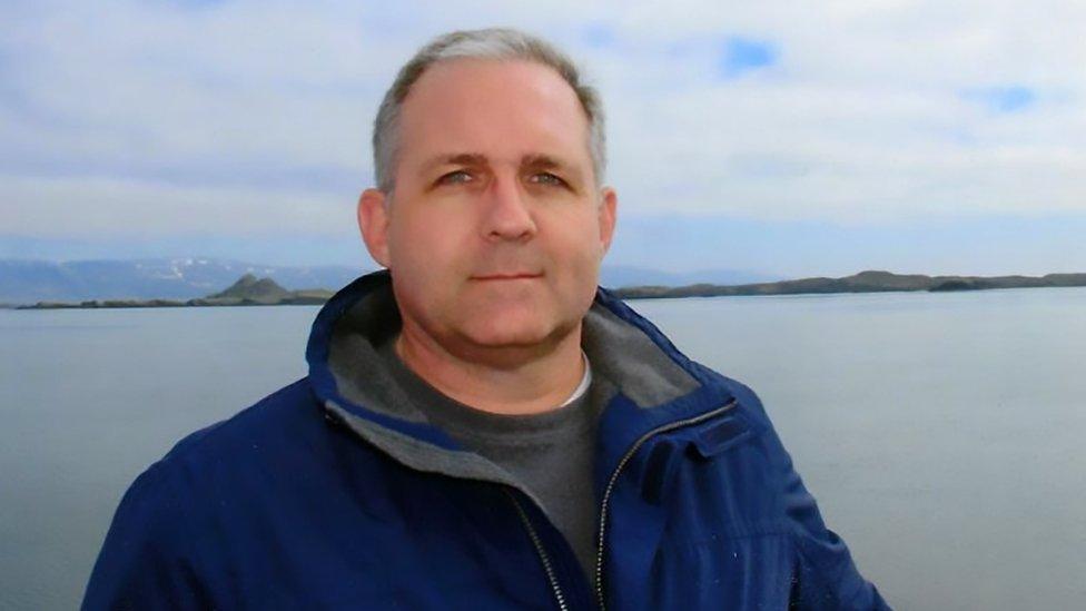 Paul Whelan poses in front of a body of water