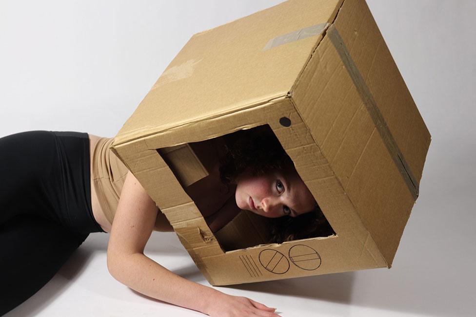 A piece of art showing a photo of a woman with a cardboard box on her head resembling a television