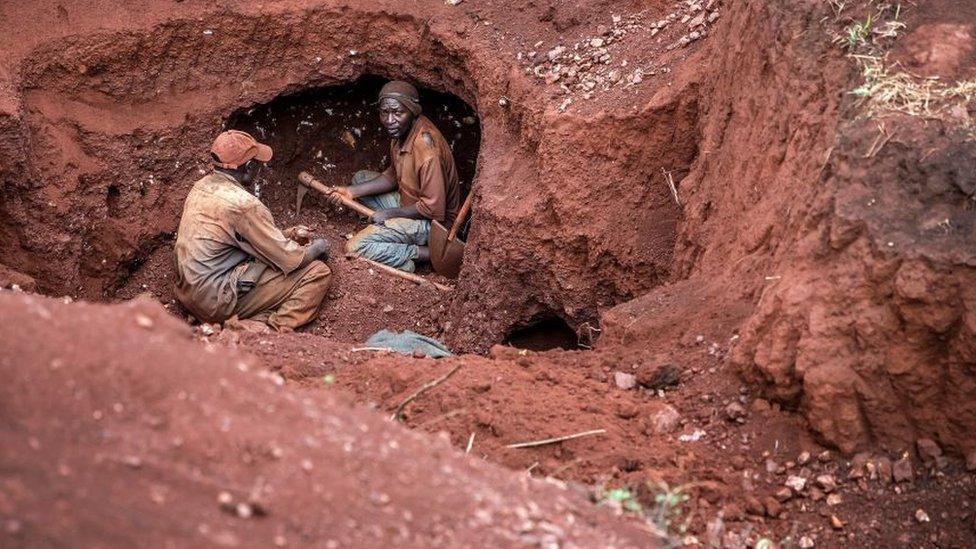 Two Tanzanian miners look for gold grains at an open-pit gold mine in Nyarugusu, Geita Region, Tanzania.