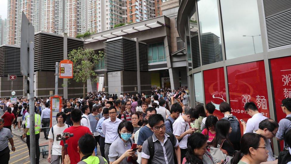 Stranded train passengers queue for a shuttle bus after Anti-extradition bill protesters disrupted train services