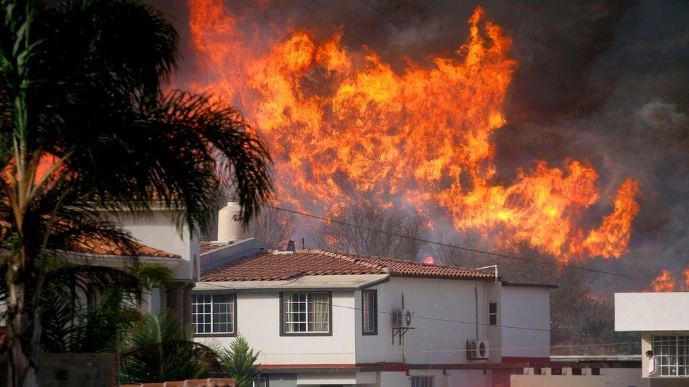 Flames engulf the hillside near a home in southern California.