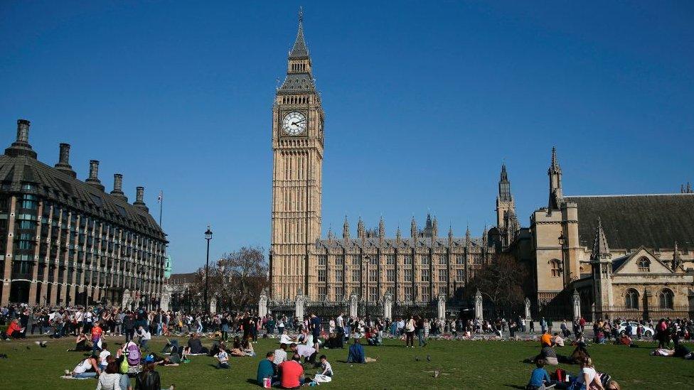 People sitting on the lawn in front of parliament