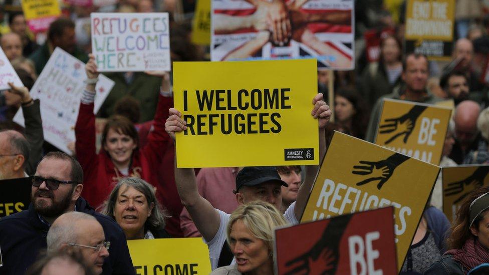 A man holds a placard at the Refugees Welcome march.