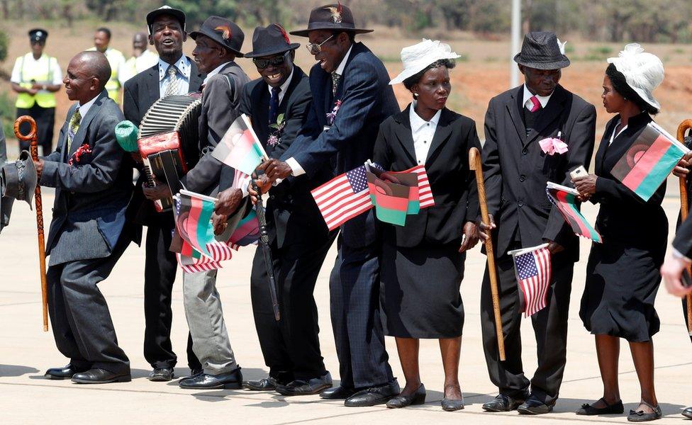 Malawians hold flags as U.S. first lady Melania Trump arrives in Lilongwe, Malawi, October 4, 2018.