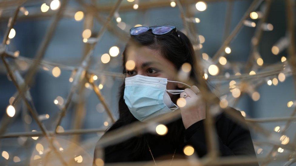 People stand by Christmas lights outside Manchester Town Hall walk-in vaccination centre where soldiers are helping to administer Covid-19 vaccinations on December 14, 2021