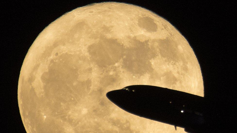 An aircraft in front of the supermoon