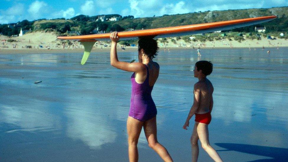 Linda Sharp holding a 9ft board on her head after being in the sea at Horton/Port Eynon on Gower