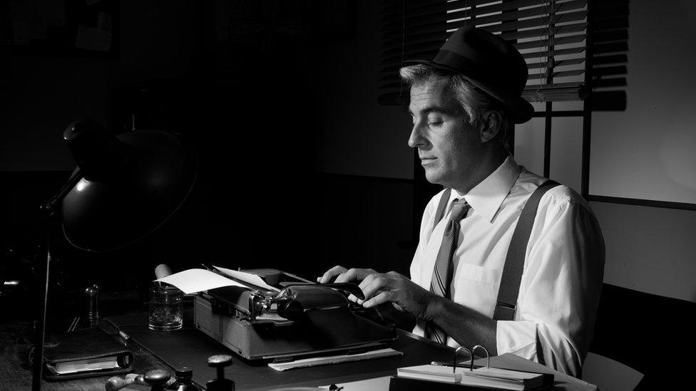 A black and white image of a man typing frantically on a typewriter