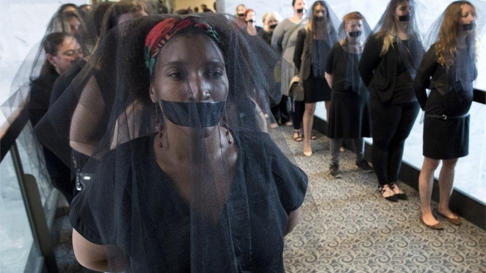 Women with black veils and black tape over their mouths in protest of Kavanaugh line up outside the hearing room