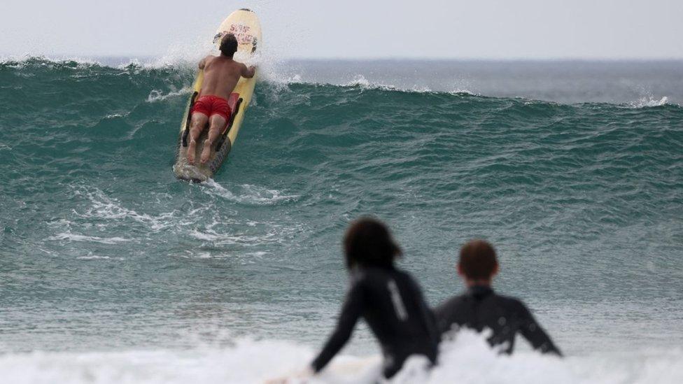 An RNLI Lifeguard uses a rescue board during hot weather at Perranporth beach, in Perranporth, Cornwall