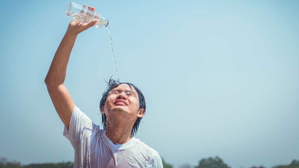 Person pouring a bottle of water over themselves