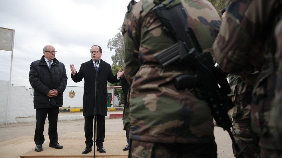 French President Francois Hollande, right, flanked by French defense minister Jean-Yves Le Drian addresses French soldiers at the Iraqi Counter Terrorism Service Academy on the Baghdad Airport Complex in Baghdad, Iraq, Monday, Jan. 2, 2017.