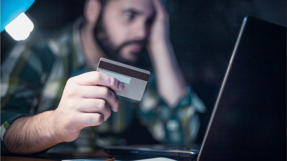 Close-up of a man paying bills using a laptop and a credit card - stock photo