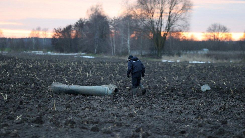 An investigator walks near a fragment of the munition