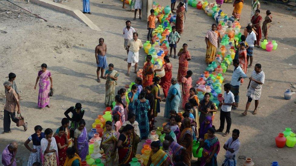 Indian residents queue with plastic recipients to get drinking water from a distribution tanker in the outskirts of Chennai on May 29, 2019.