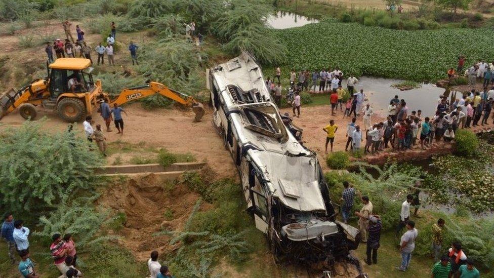 Onlookers and Indian police gather around the crumpled remains of a bus that crashed on the Delhi-Agra expressway, near Agra on July 8, 2019.