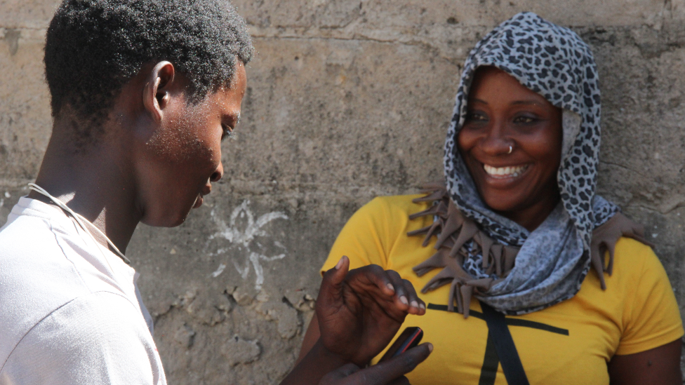 Pelé Bambina checking his phone for a money transfer from a mota taxi customer in Pemba, Mozambique - May 2022