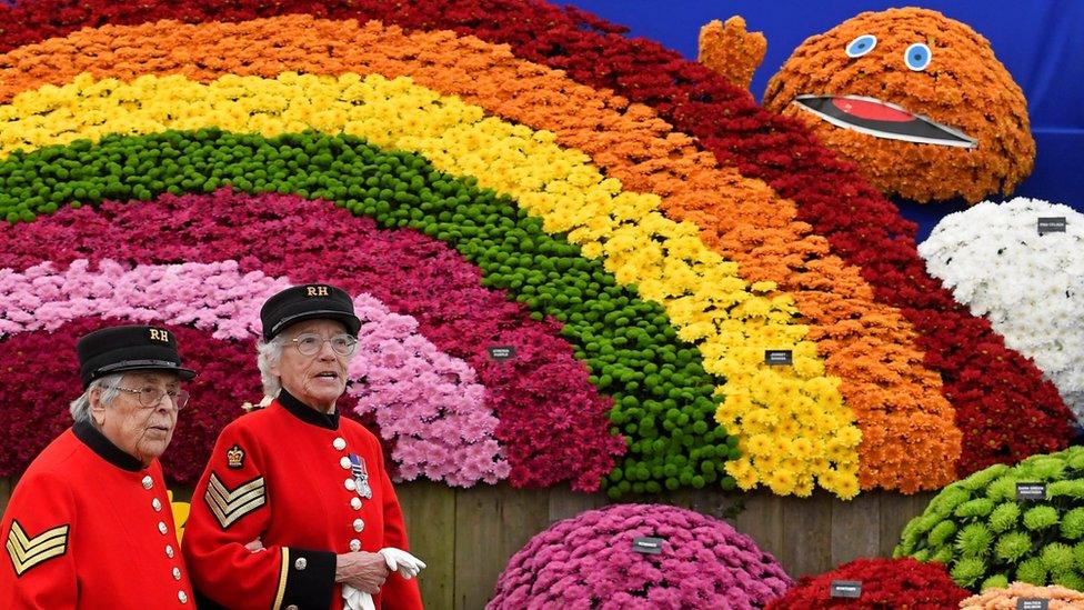 Chelsea Pensioners walk past a floral display at Chelsea Flower Show