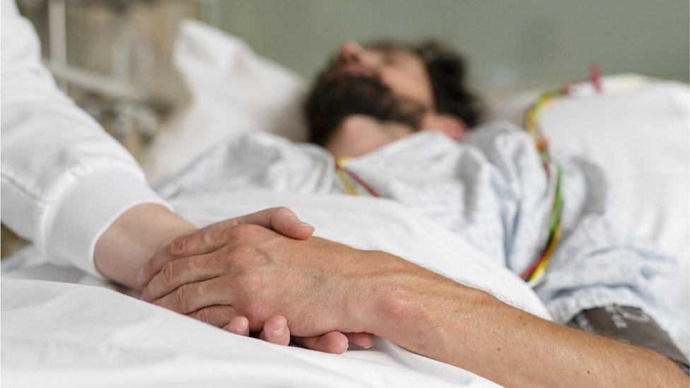 Healthcare staff caring for a patient in hospital bed - stock photo