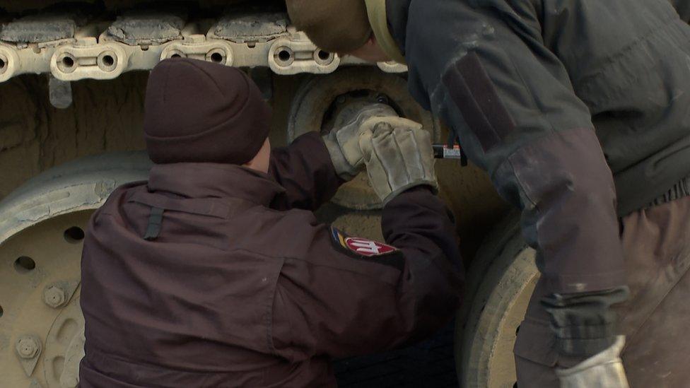 Two soldiers inspect a tank