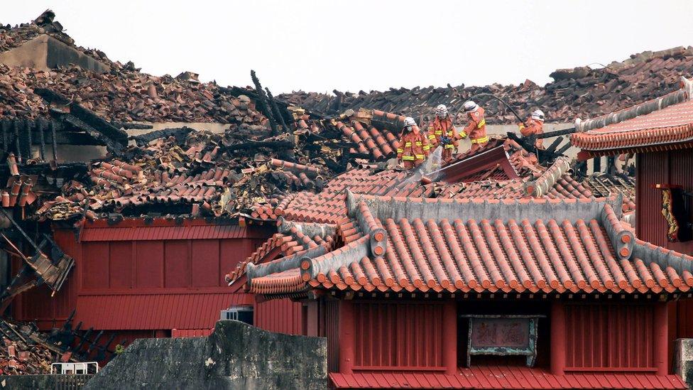 Firefighters inspect the heavily damaged Shuri Castle in Naha