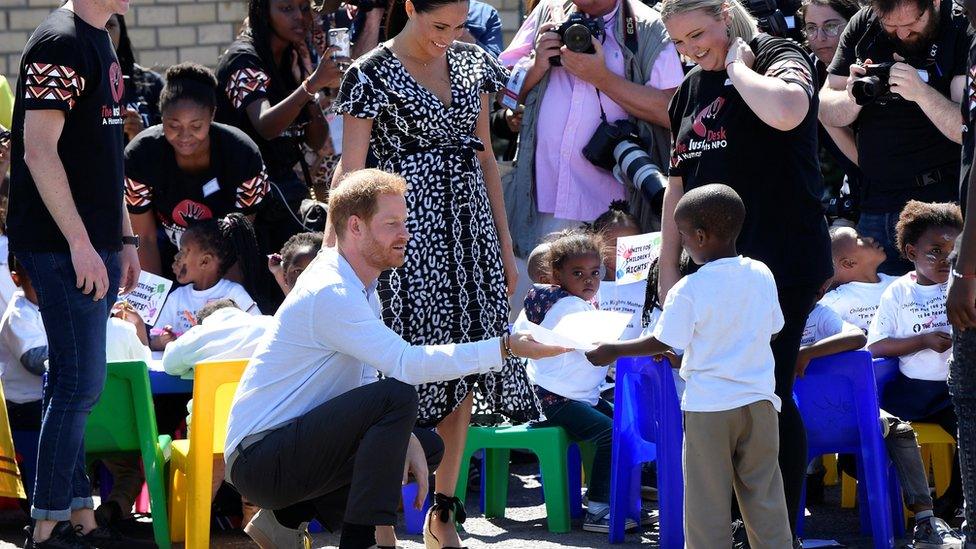 Prince Harry is presented with a drawing by a young boy