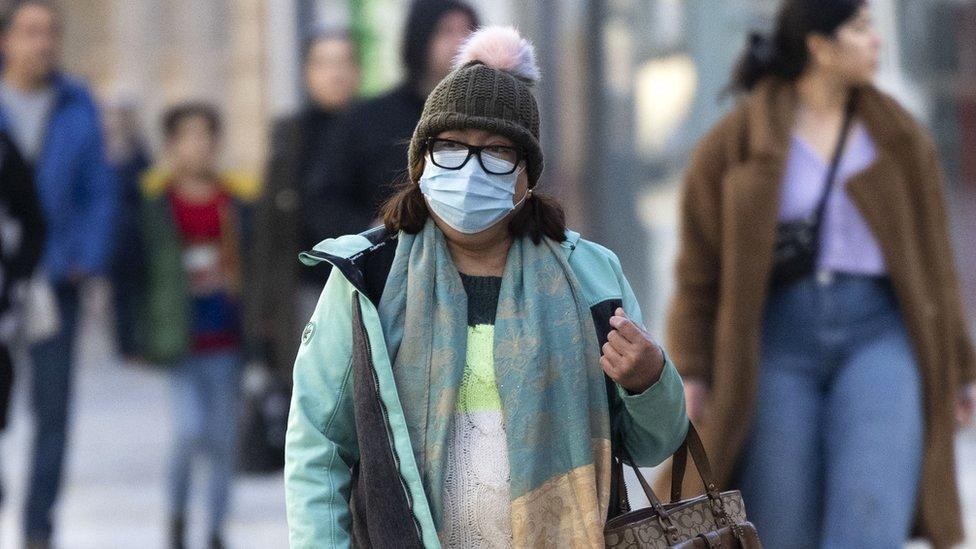 A person walks down the street in a mask