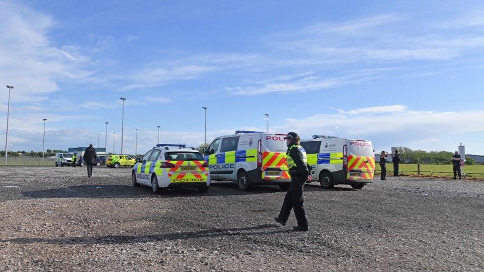 Police officers and vehicles next to the playing field