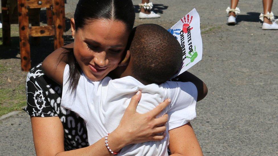 Meghan shares a hug with a youngster