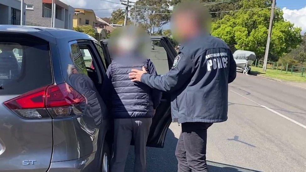 An Australian Federal Police officer (left) and one of the men arrested