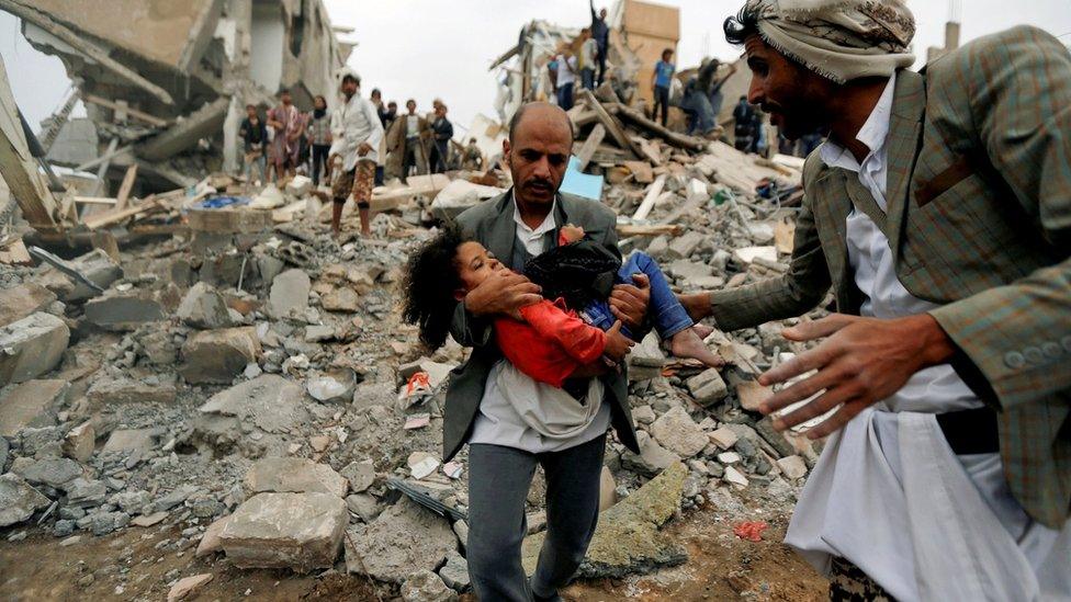 A man carries Buthaina Muhammad Mansour, a Yemeni girl rescued from the site of a Saudi-led coalition air strike that killed eight of her family members in Sanaa on 25 August 2017