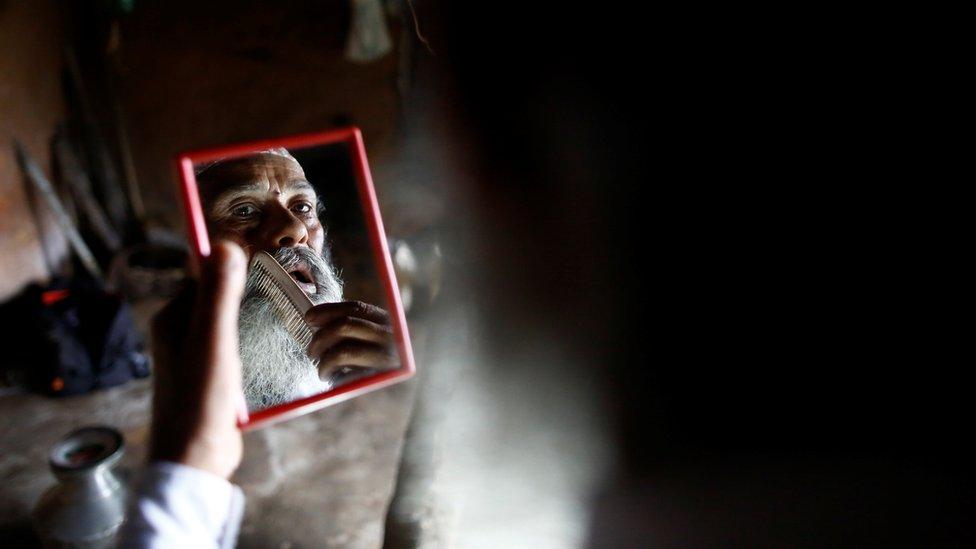 Mr Kami combs his beard while getting ready for school