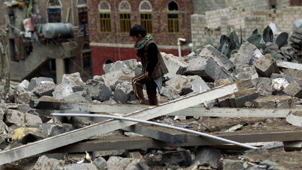 A Yemeni child inspects the rubble of a house